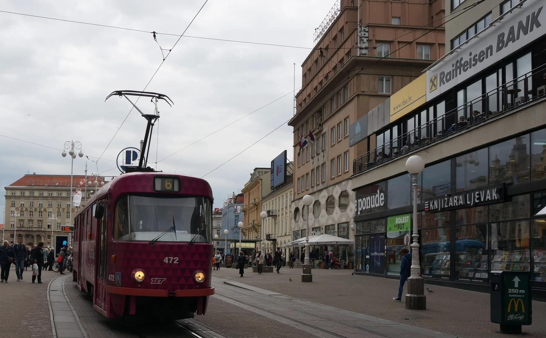 Red Zagreb tram approaching through Ban Jelacic Square beneath overhead wires