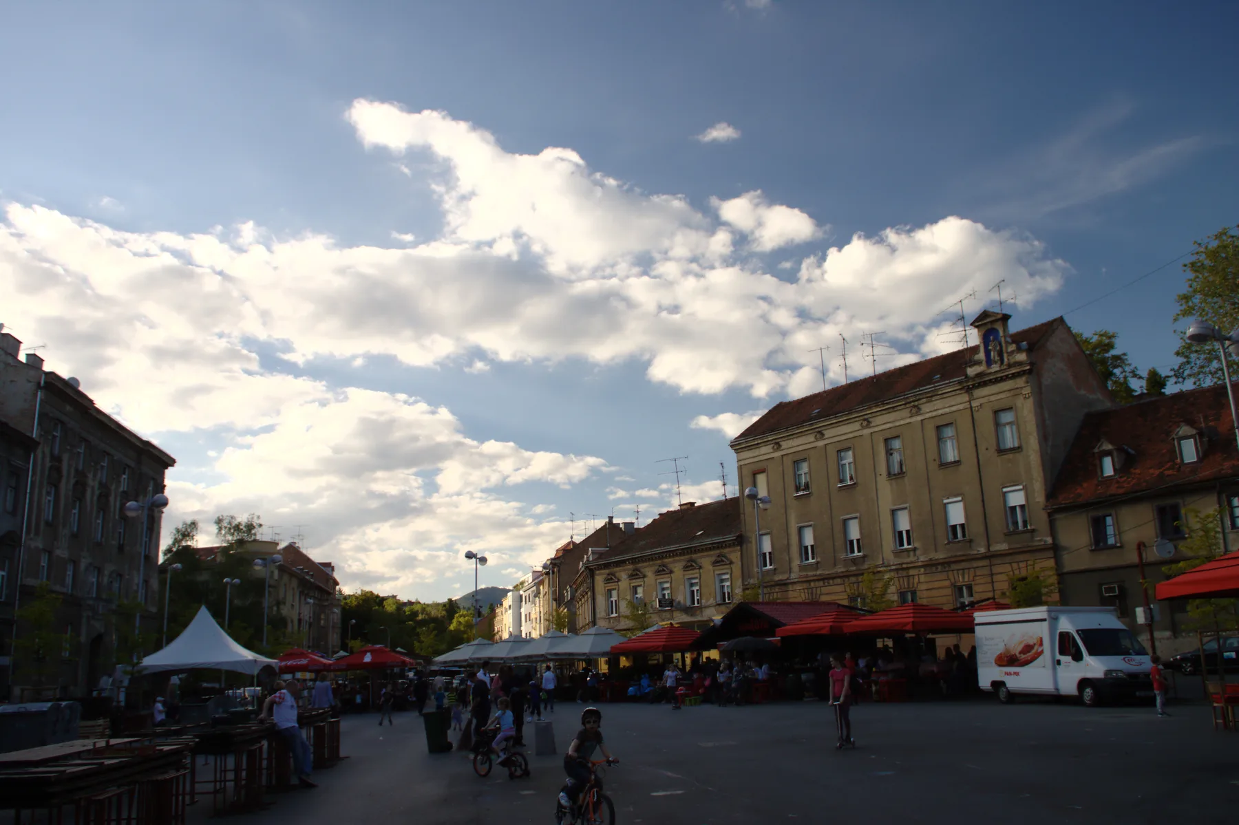 Britanski trg stalls and people beneath a dramatic evening sky