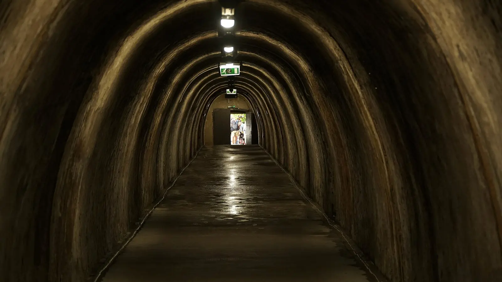 Long dark Grič Tunnel passage leading toward a daylight exit