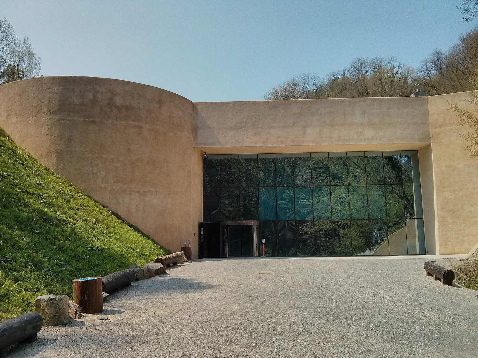 Earth-toned curved façade and glazed entrance of the Krapina Neanderthal Museum