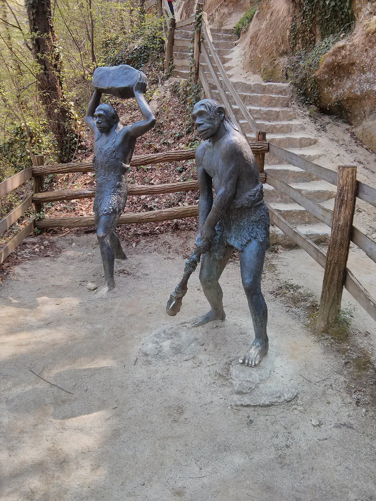 Neanderthal reconstruction figures beside steep steps on the wooded Hušnjakovo path