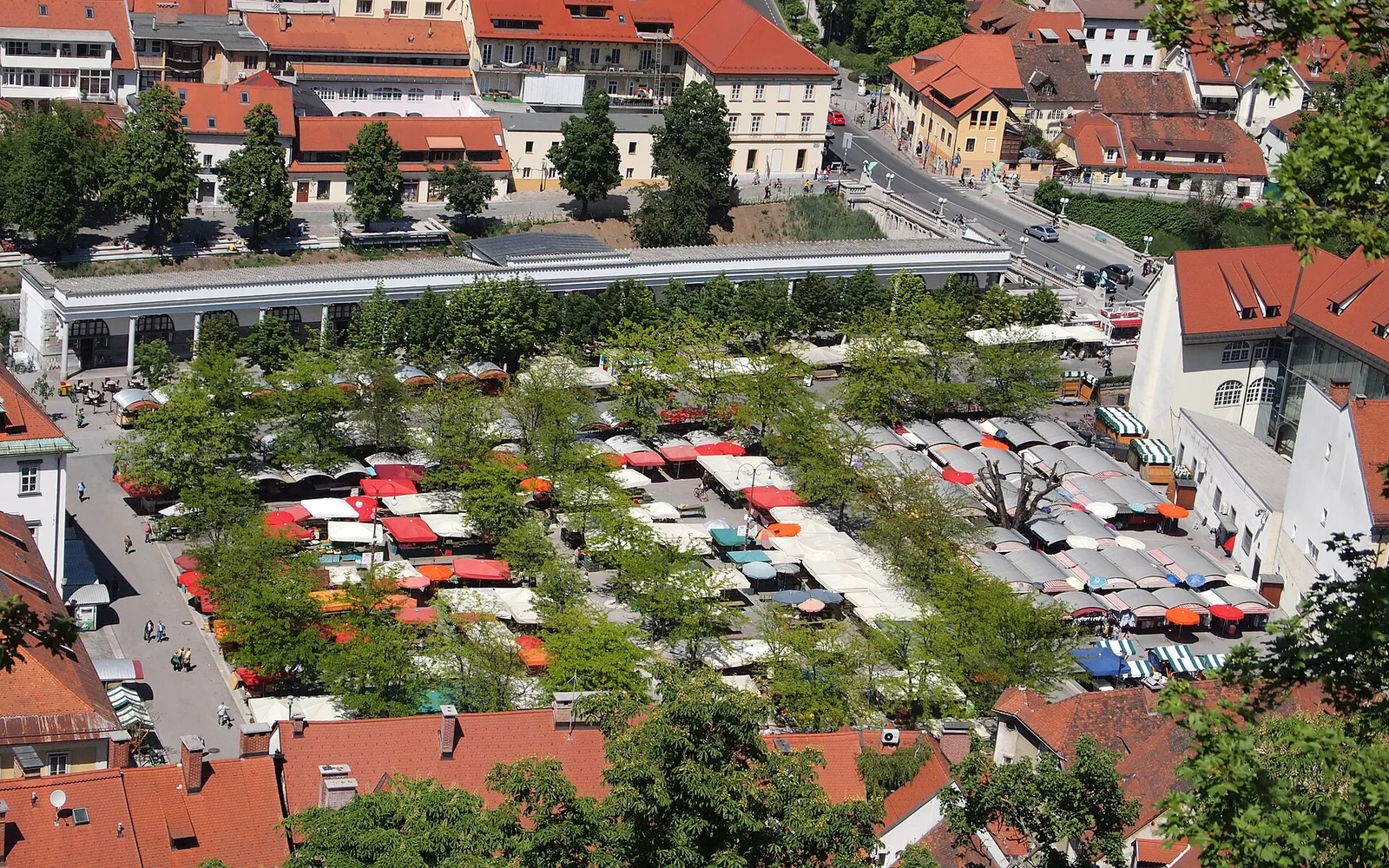 Open-air stalls and Plečnik's long riverside market colonnade in central Ljubljana