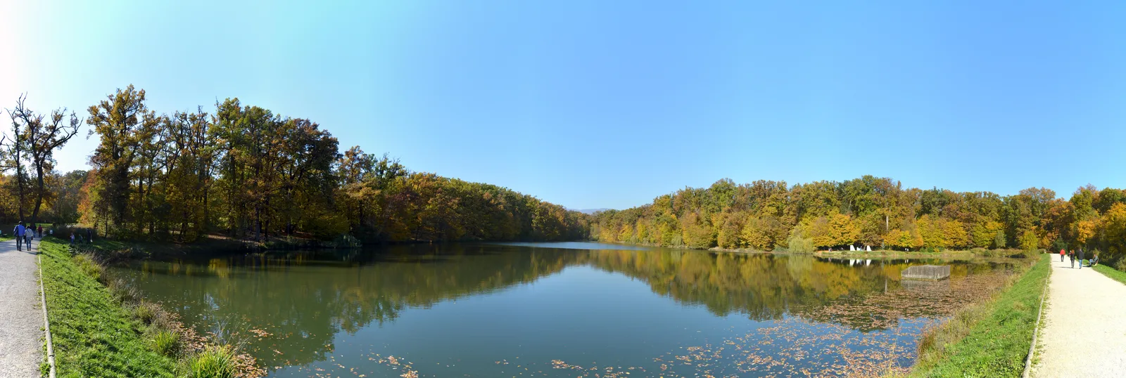 Wide autumn panorama across a calm lake in Maksimir Park