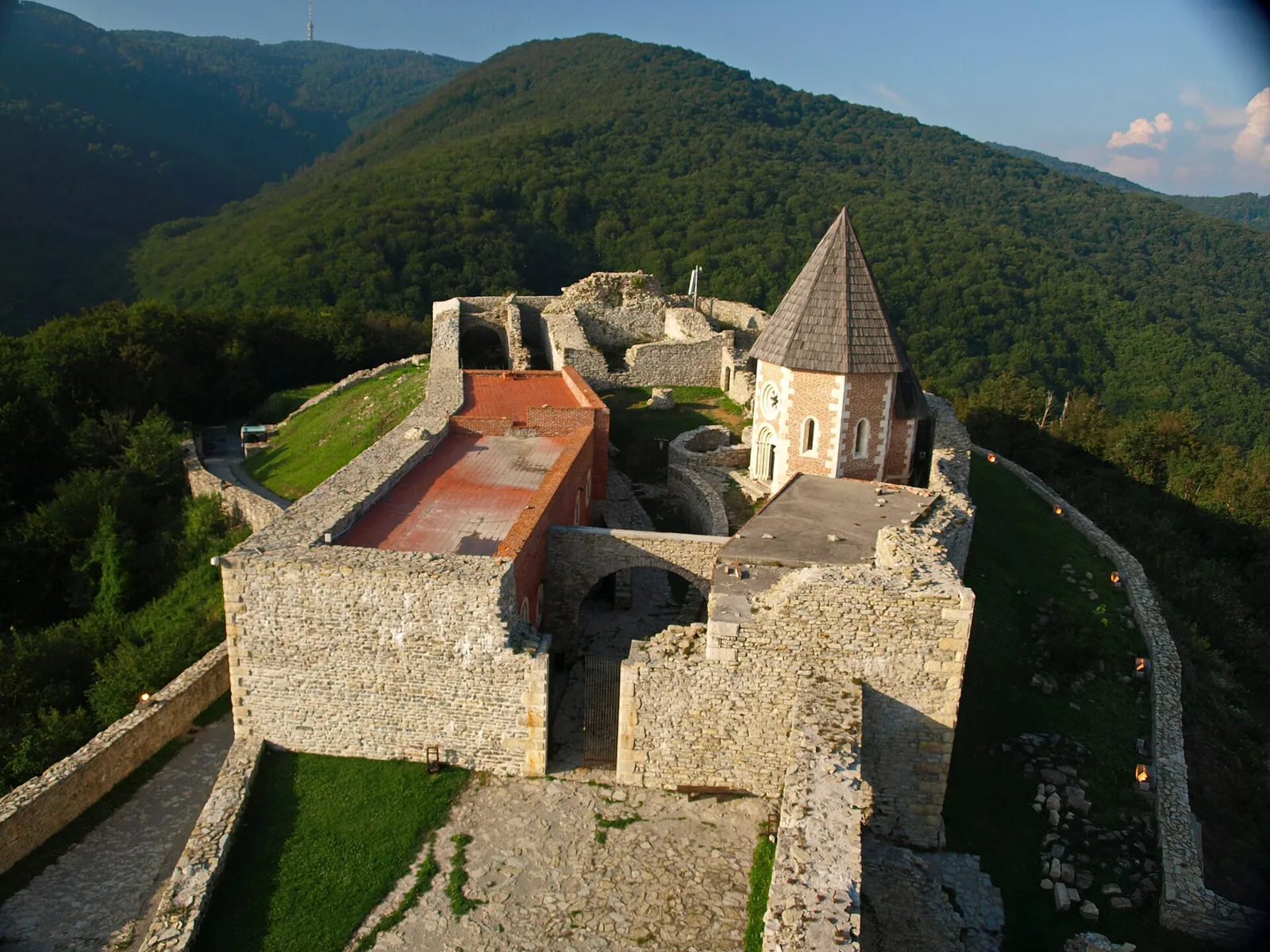 Elevated view into Medvedgrad fortress with stone walls, chapel and forested Medvednica behind