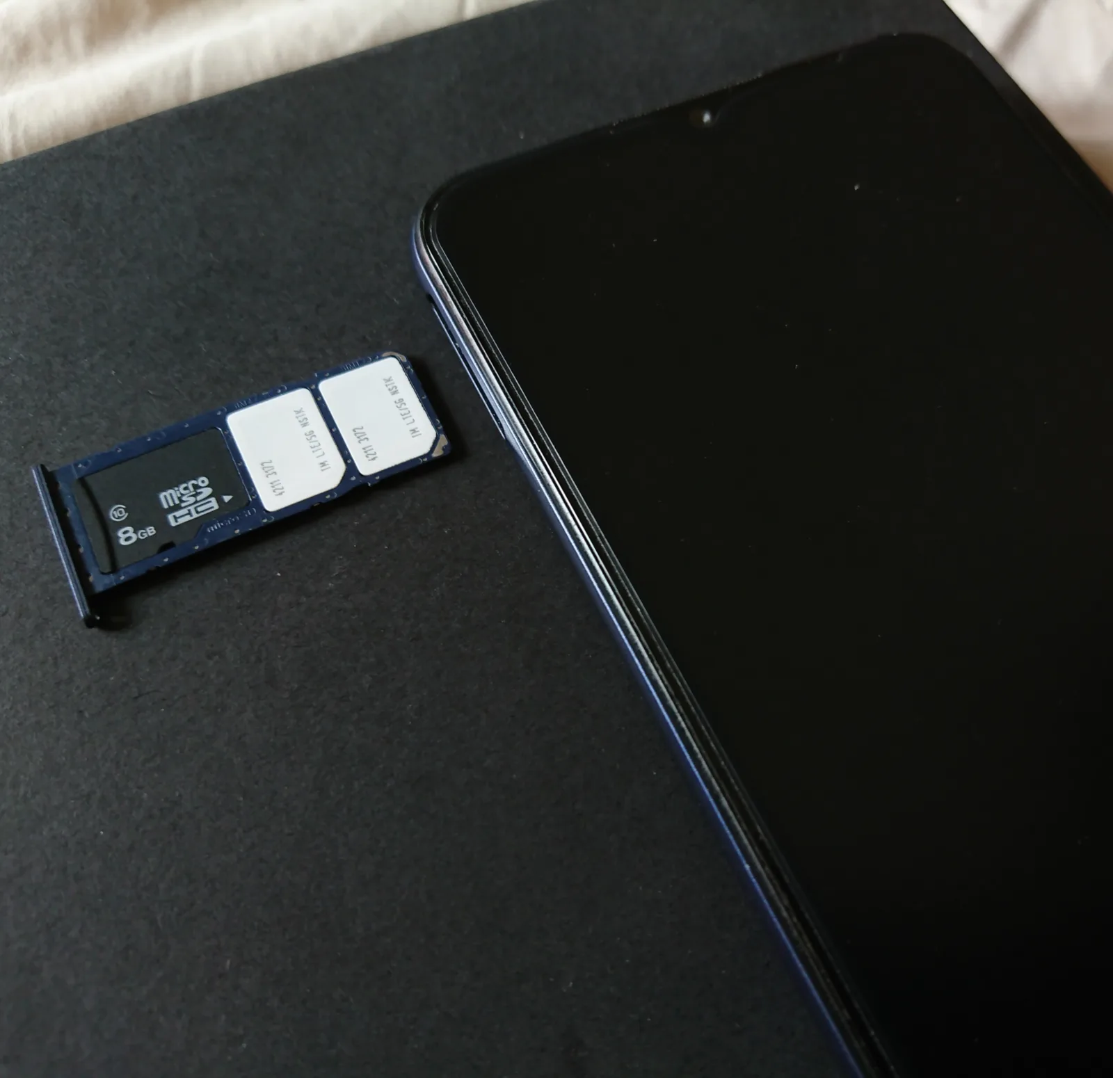 Modern smartphone with its SIM tray removed beside two SIM cards