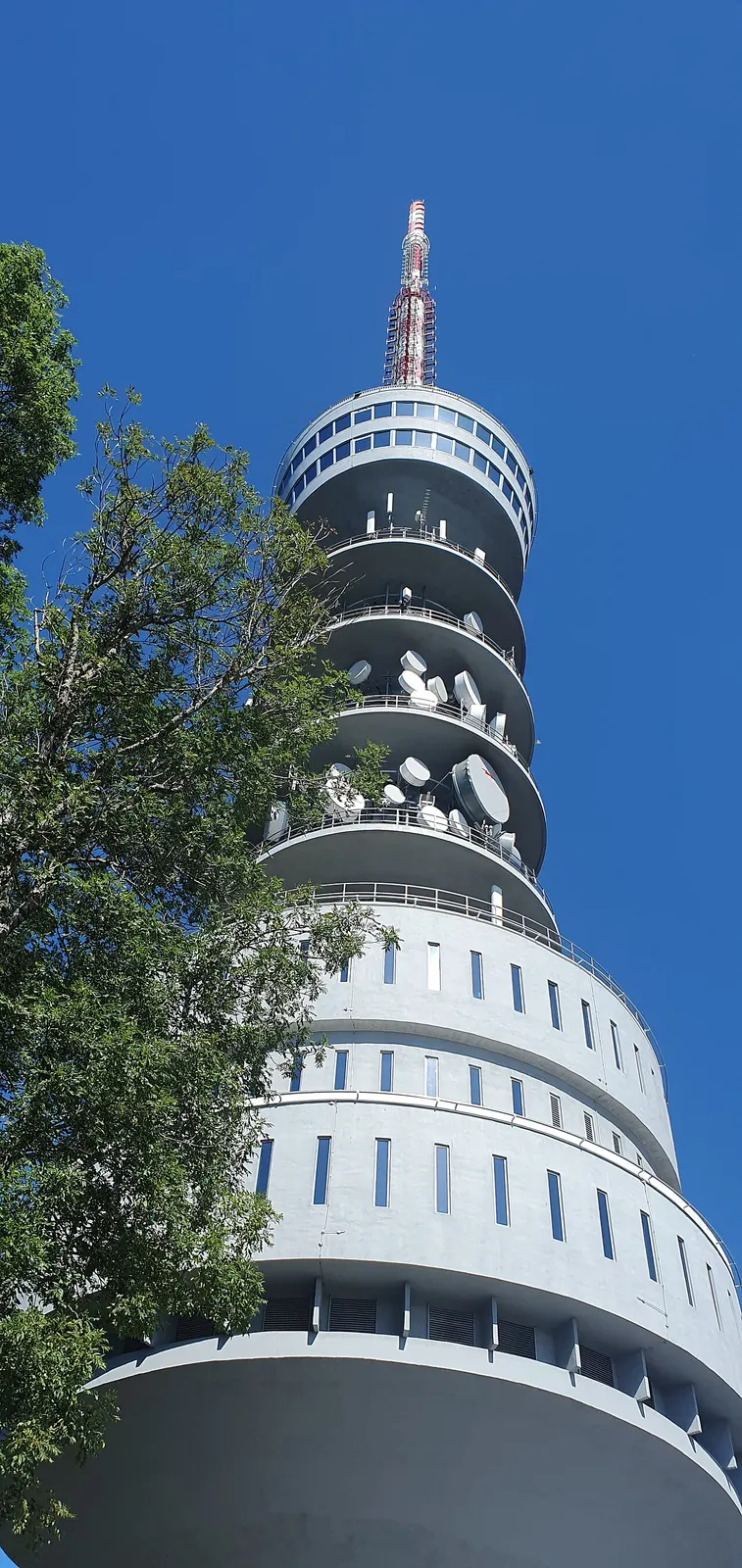 The cylindrical Zagreb television tower rising above trees at Sljeme