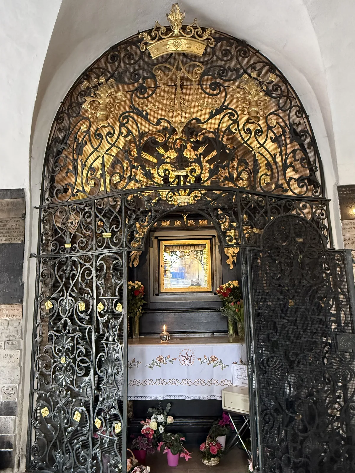 Ornate grille, altar cloth and votive flowers at the Stone Gate shrine