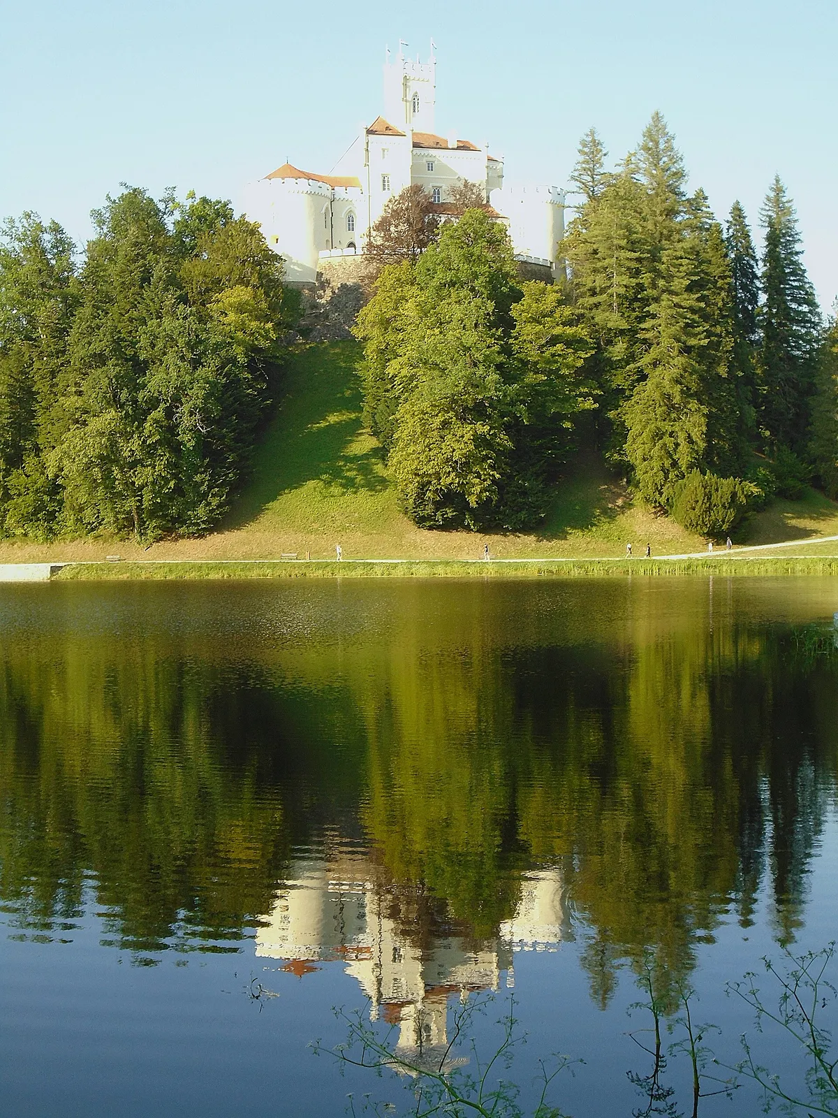 Trakošćan Castle and its white towers reflected across the lake