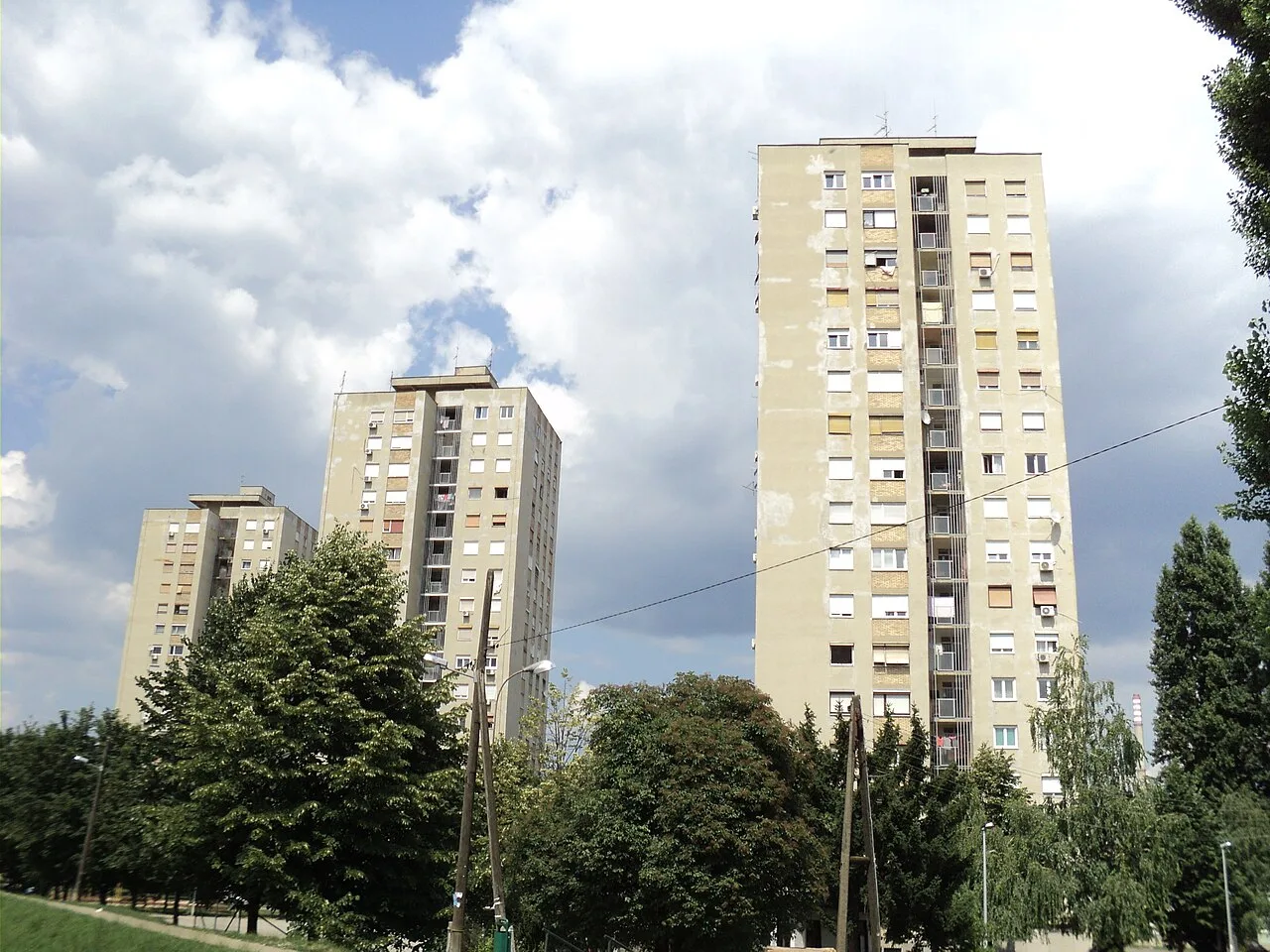 Residential towers rising behind mature trees on Fallerovo promenade in Trešnjevka