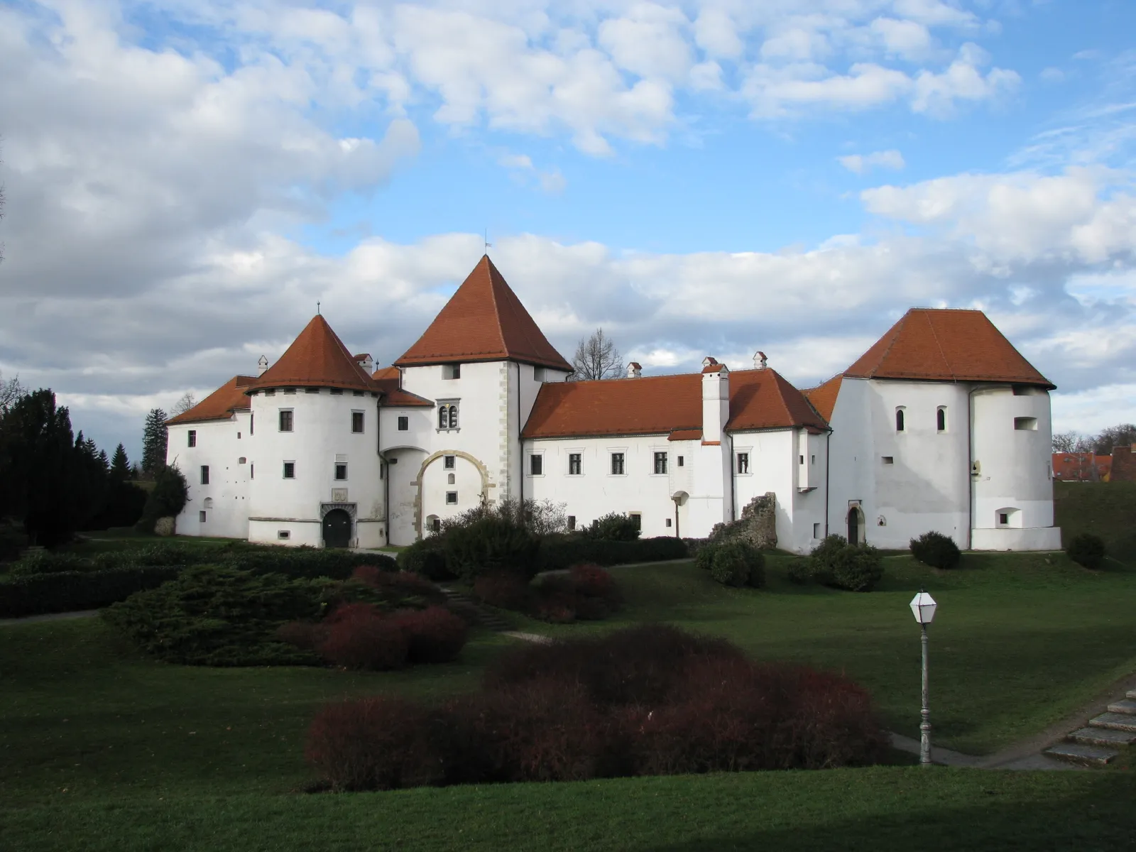 White towers and red roofs of Stari grad fortress in Varaždin above green earthworks