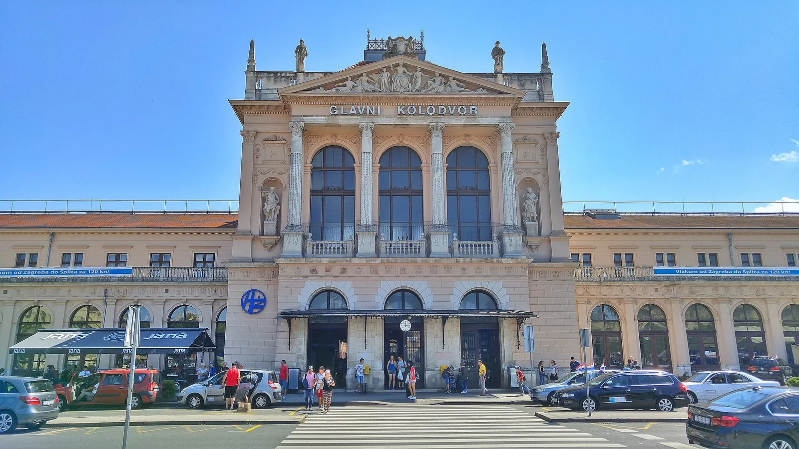 Yellow historic facade of Zagreb Main Railway Station behind its tram stops